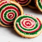 A close-up of a pinwheel cookie featuring vibrant red and green swirls, showcasing its festive and colorful design.