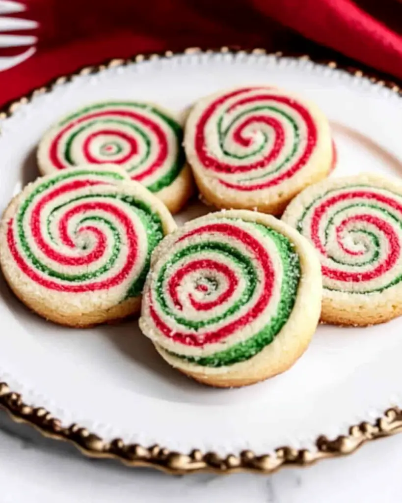 A plate of colorful pinwheel cookies displayed on a festive red and green tablecloth. Perfect for holiday celebrations!
