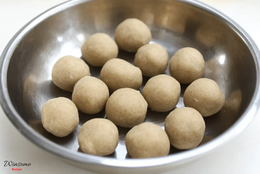 Unbaked dough balls neatly arranged in a steel bowl, ready to be baked into delicious cookies.