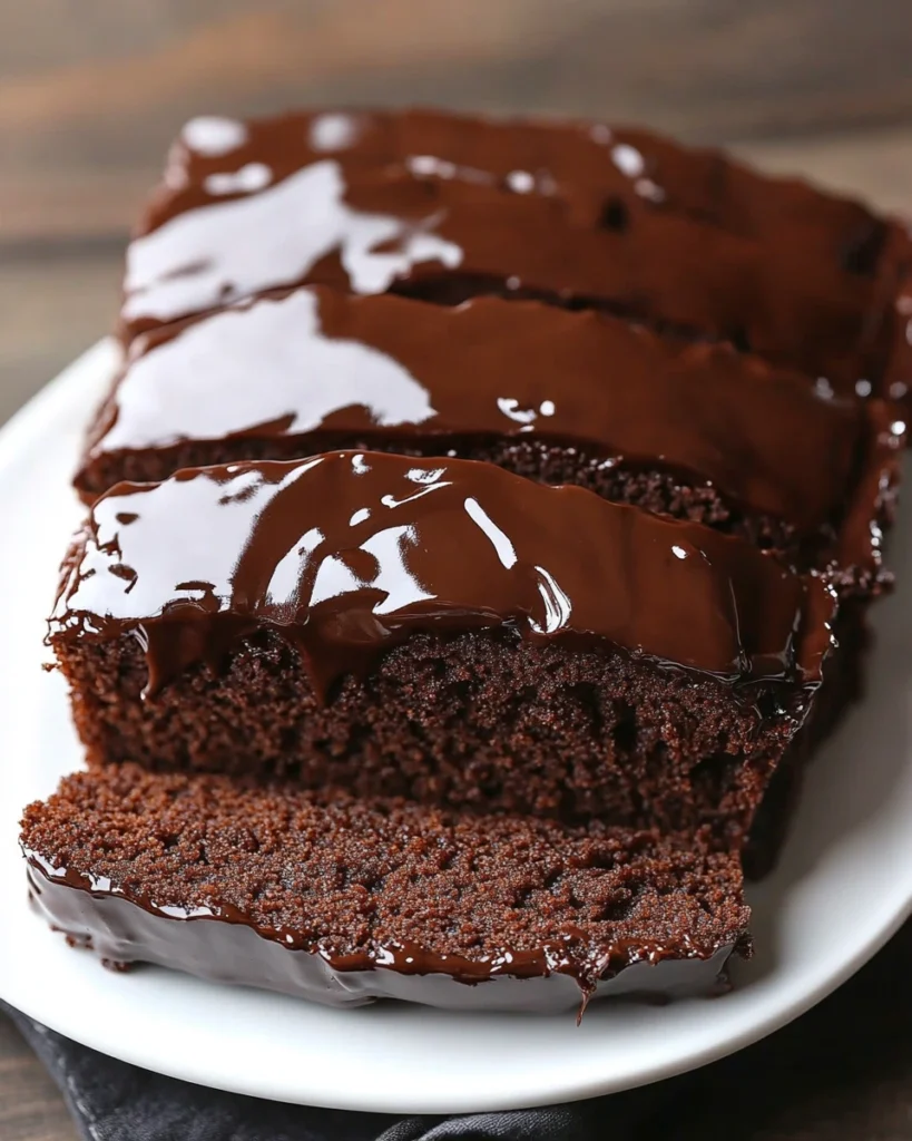 close-up image of a sliced chocolate pound cake with glossy chocolate glaze