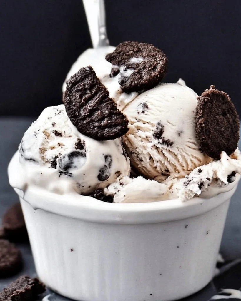 A bowl of cookies and cream ice cream topped with crushed cookies and Oreos, creating a delicious treat.