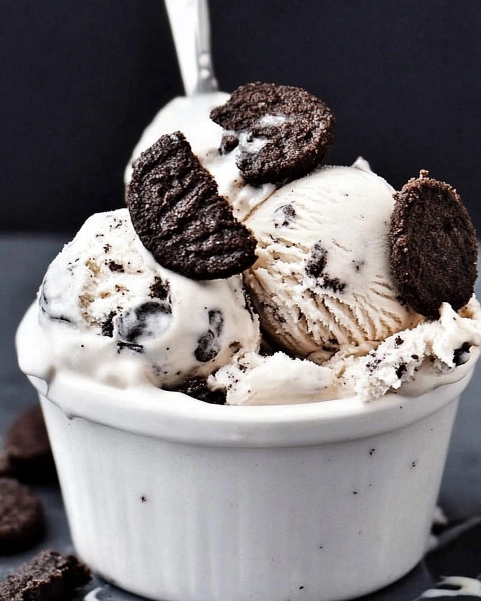 A bowl of cookies and cream ice cream topped with crushed cookies and Oreos, creating a delicious treat.