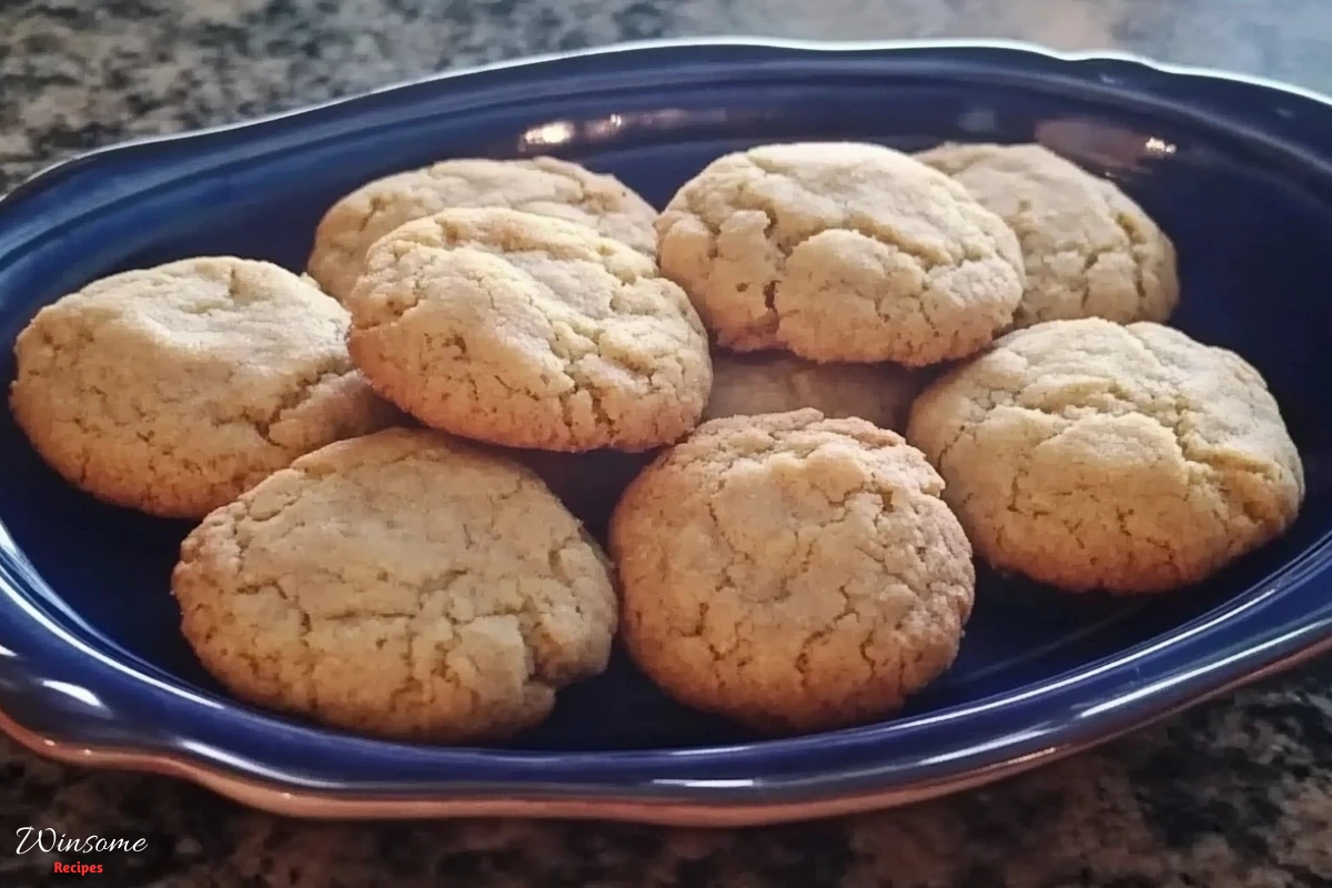 A blue bowl filled with walnut cookies sits invitingly on a wooden table.