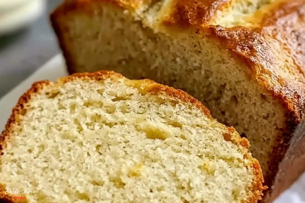 A loaf of 4 ingredient banana bread with a slice removed, showcasing its moist texture and golden-brown crust.