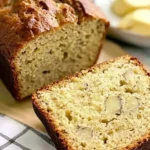 A loaf of four-ingredient banana bread topped with butter and a knife resting beside it.