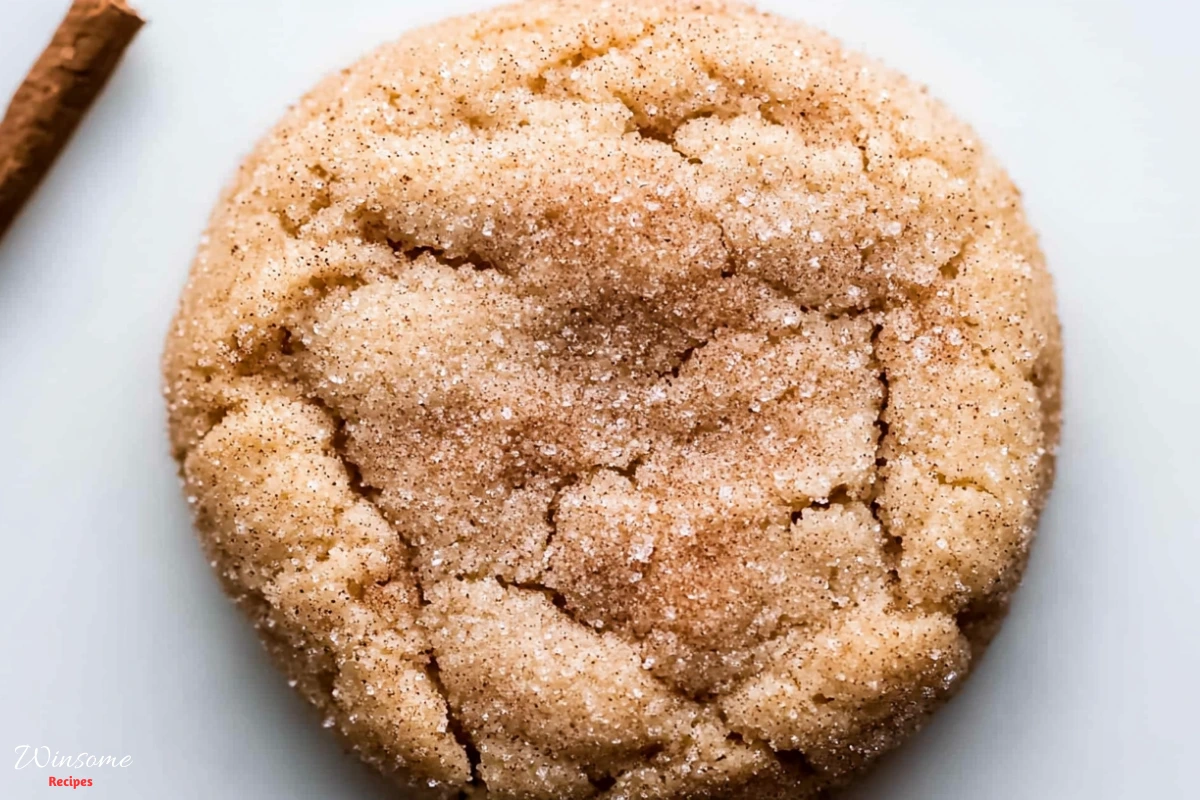 A delicious sugar cookie topped with cinnamon sticks, resting on a clean white surface, perfect for a snickerdoodle treat.