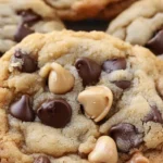 Caramel chocolate chip cookies topped with peanuts and chocolate chips, arranged on a white plate.