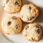Three coconut chocolate chip cookies arranged on a white plate, showcasing their delicious, golden-brown texture.